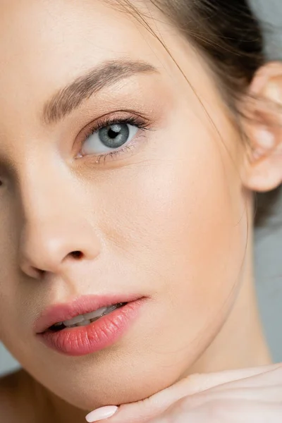 Close up view of young woman with perfect skin looking at camera isolated on grey — Stock Photo