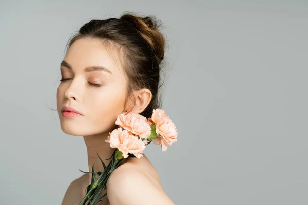 Pretty woman with natural makeup posing with carnations isolated on grey — Foto stock