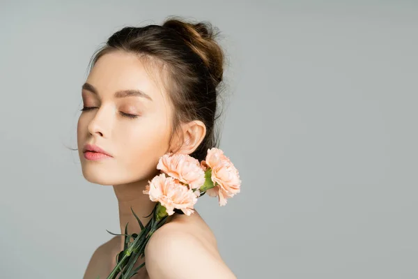 Pretty woman with natural makeup posing with carnations isolated on grey — Photo de stock