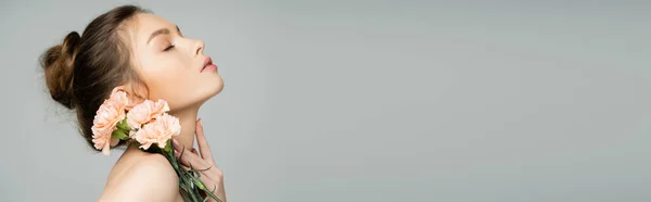 Young woman with perfect skin posing near carnations isolated on grey, banner — Stock Photo
