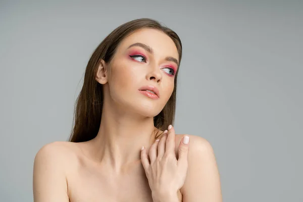 Pretty young woman with naked shoulders and bright makeup isolated on grey — Stock Photo