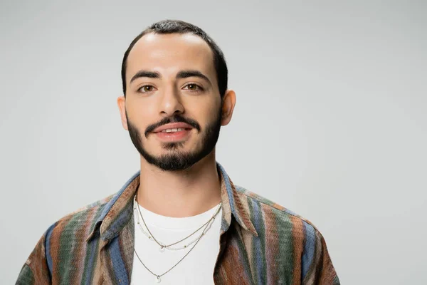 Portrait of young bearded man in colorful shirt smiling at camera isolated on grey — Stock Photo
