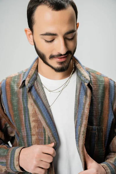 Portrait of young bearded man in colorful shirt and necklaces isolated on grey — Stock Photo