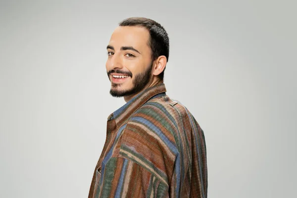 Portrait of joyful bearded man in trendy shirt looking at camera isolated on grey — Stock Photo