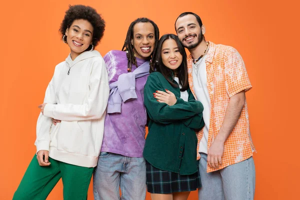 Felici amici multietnici che indossano abiti eleganti e posa isolata su arancione — Foto stock
