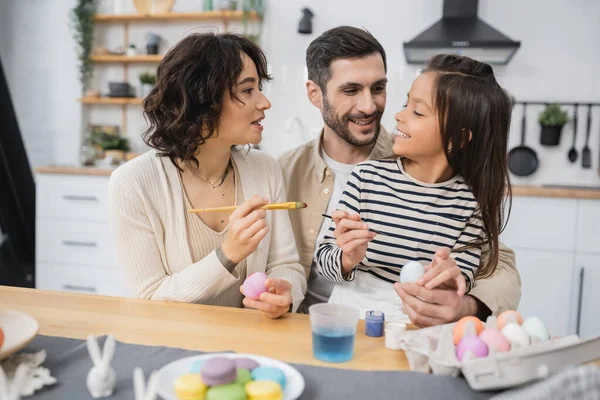 Positive family painting Easter eggs and talking at home — Fotografia de Stock