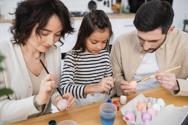 Батьки і дитина малюють великодні яйця на кухні — стокове фото