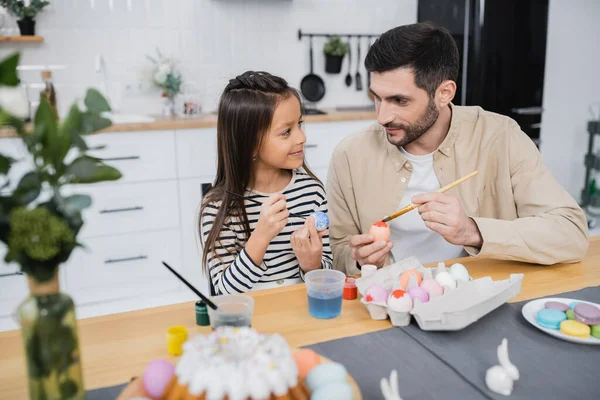 Homem falando com a filha enquanto colore ovos de Páscoa na cozinha — Fotografia de Stock