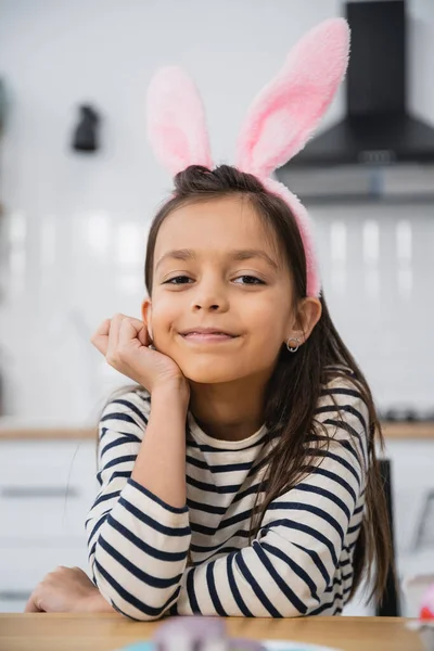 Smiling girl in Easter bunny ears headband looking at camera at home — Stock Photo