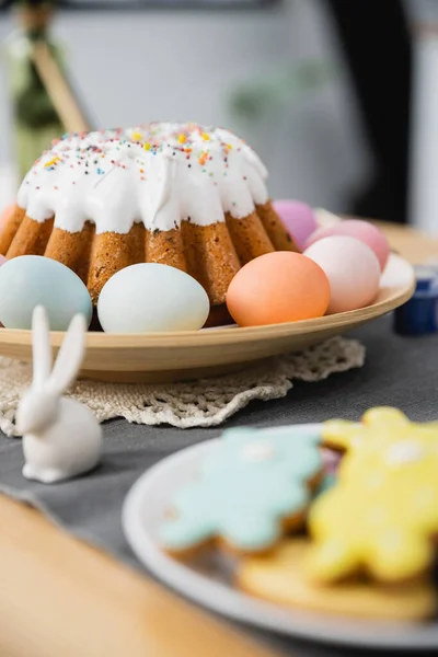 Bolo de Páscoa e ovos coloridos perto de coelho na mesa — Fotografia de Stock