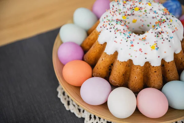 Високий кут зору солодкого пирога і розфарбовані яйця пастельних кольорів на столі в домашніх умовах — стокове фото