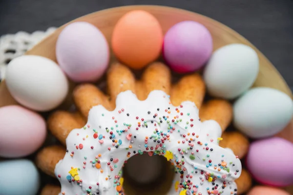 Vue du dessus du gâteau de Pâques et des oeufs de couleurs pastel peints flous sur la table — Photo de stock