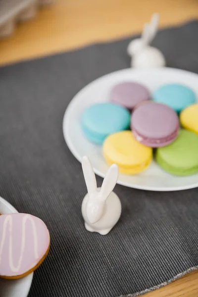 Easter rabbit figurine near colorful macaroons on table at home — Stock Photo