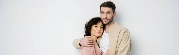 Bärtiger Mann umarmt brünette Frau auf weißem Hintergrund, Banner — Stockfoto