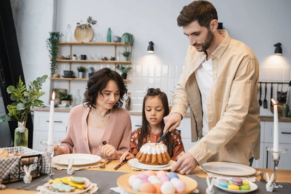 Man cutting Easter cake near family during dinner at home — Fotografia de Stock