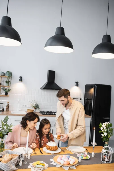 Man holding Easter cake near wife and daughter during dinner at home — Stock Photo