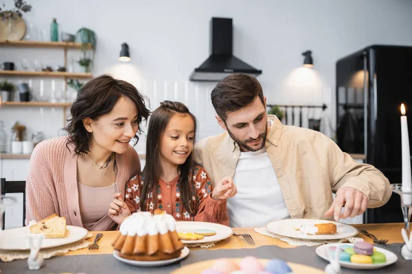 Man taking Easter cake near daughter and wife in kitchen — Fotografia de Stock