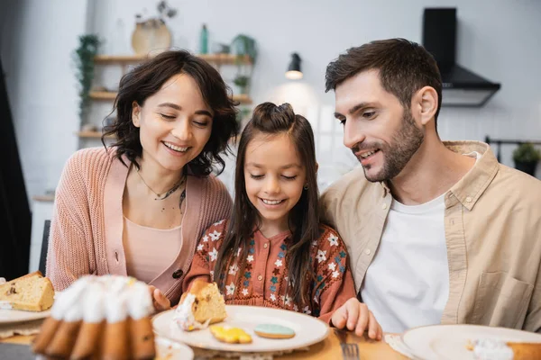 Positive parents sitting near child and Easter dinner at home — Stock Photo
