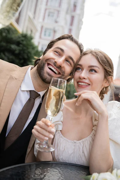 Fröhliche und junge Brautpaare mit Champagnergläsern bei der Hochzeitsfeier — Stockfoto