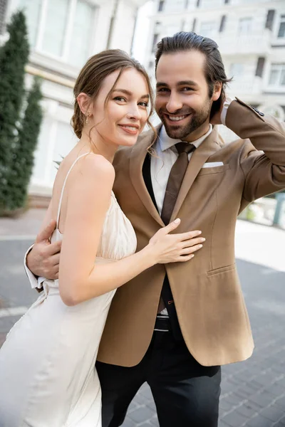 Щаслива наречена обіймає бородатого нареченого і посміхається зовні — стокове фото