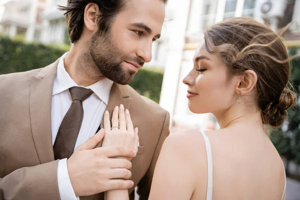 Mujer joven con anillo de boda en el dedo de pie con el novio en traje - foto de stock