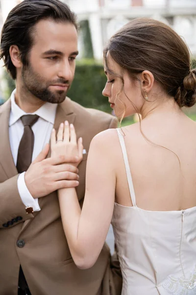 Barbudo hombre en traje con corbata mirando bonita novia al aire libre - foto de stock