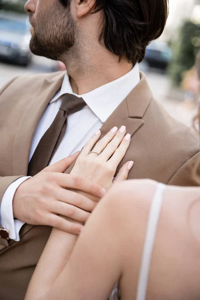 Обрезанный вид молодой женщины с обручальным кольцом на пальце, стоящей рядом с женихом в костюме — стоковое фото