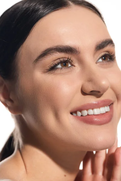 Primer plano de alegre joven con maquillaje natural mirando hacia otro lado aislado en blanco - foto de stock
