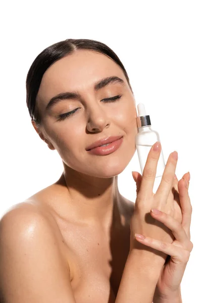 Compiaciuta giovane donna con bottiglia di trucco naturale con siero isolato su bianco — Foto stock