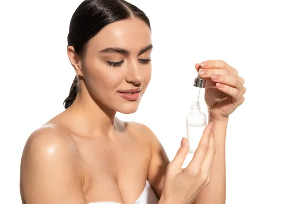 Young woman with bare shoulders holding dropper with vitamin c serum isolated on white — Stock Photo
