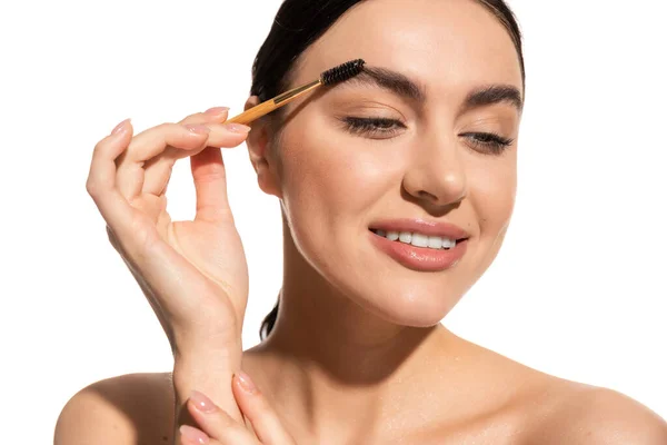 Smiling young woman styling eyebrows with brush and gel isolated on white — Stock Photo