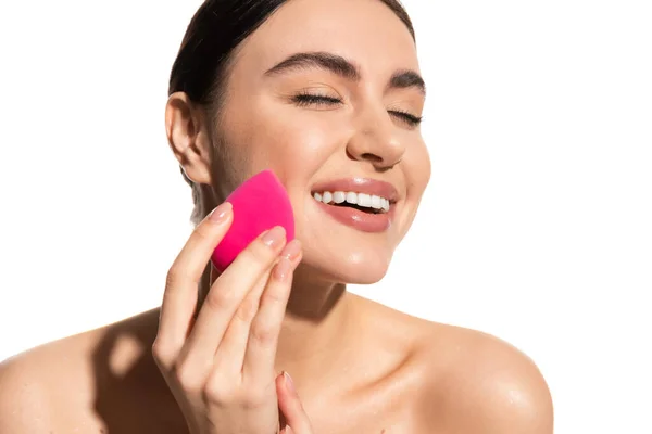 Cheerful young woman with natural makeup holding pink beauty sponge isolated on white — Photo de stock