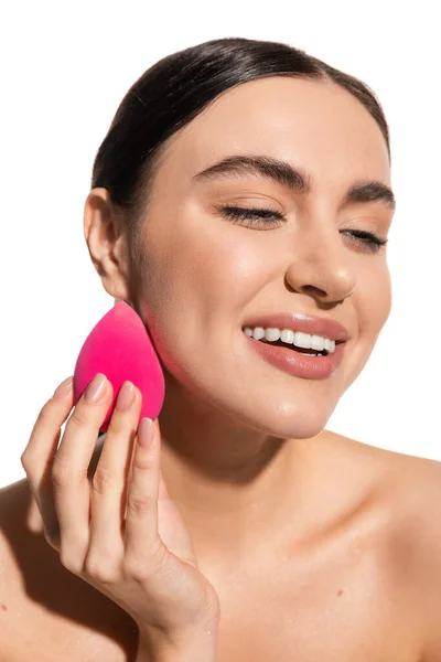 Glückliche junge Frau schminkt Foundation mit rosa Schönheitsschwamm isoliert auf weiß — Stockfoto
