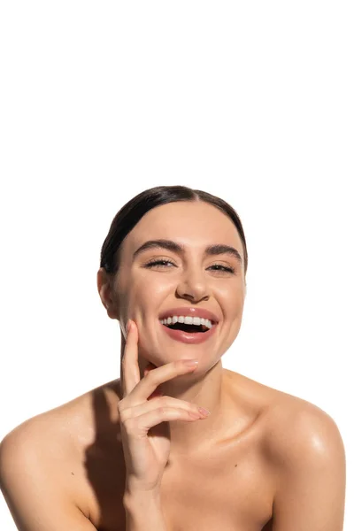 Satisfied young woman with brunette hair laughing and touching face isolated on white — Stock Photo