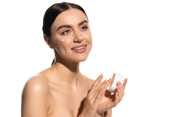 Glückliche junge Frau mit nackten Schultern hält Glas mit feuchtigkeitsspendender Gesichtscreme isoliert auf weiß — Stockfoto