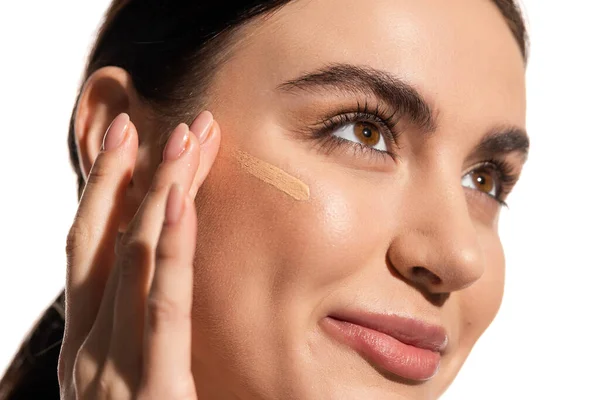 Close up of young woman with soft skin applying makeup foundation on cheek with fingers isolated on white — Stock Photo