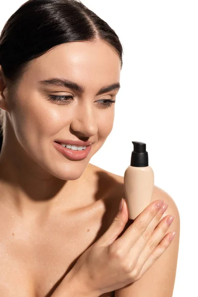 Cheerful young woman holding bottle with liquid face foundation isolated on white — Photo de stock