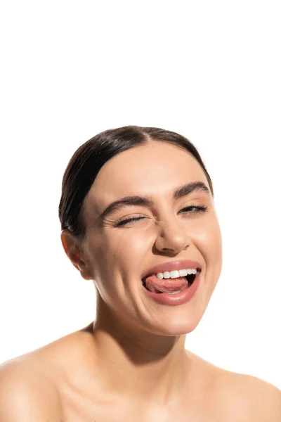 Крупним планом щаслива молода жінка з бездоганним натуральним макіяжем, що стирчить язиком ізольовано на білому — стокове фото