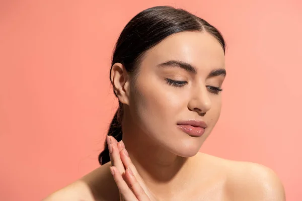 Young woman with bare shoulders and soft skin looking away isolated on pink — стоковое фото