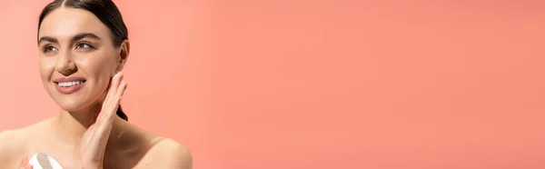 Щаслива молода жінка з голими плечима тримає банку з живильним кремом ізольовано на рожевому, банер — стокове фото