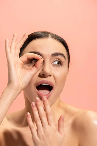 Erstaunt Frau bedeckt geöffneten Mund und zeigt ok Zeichen isoliert auf rosa — Stockfoto