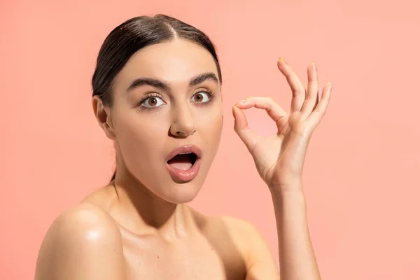Surprised woman with opened mouth showing ok sign isolated on pink — Stock Photo