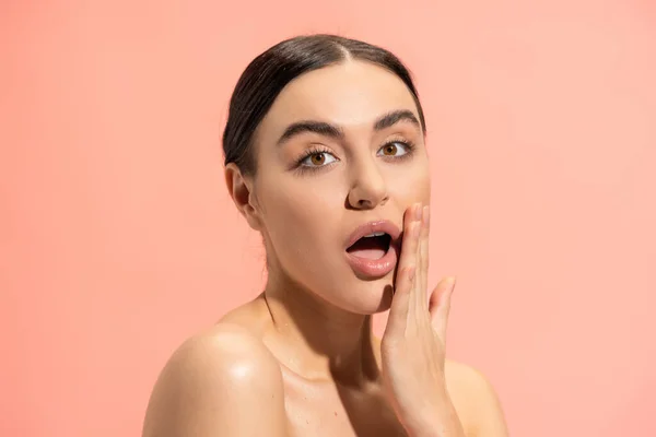 Surprised woman with opened mouth touching face isolated on pink — Stockfoto