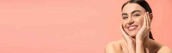 Чарівна молода жінка з голими плечима дивиться на камеру, посміхаючись ізольовано на рожевому, банер — стокове фото