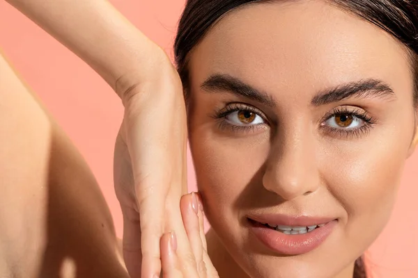 Close up view of charming young woman with clenched hands looking at camera isolated on pink — Stock Photo