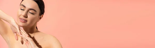 Charming woman with clenched hands and closed eyes posing isolated on pink, banner — Stock Photo