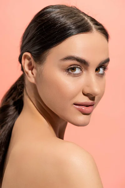 Portrait of charming young woman with naked shoulder looking at camera isolated on pink — Stock Photo