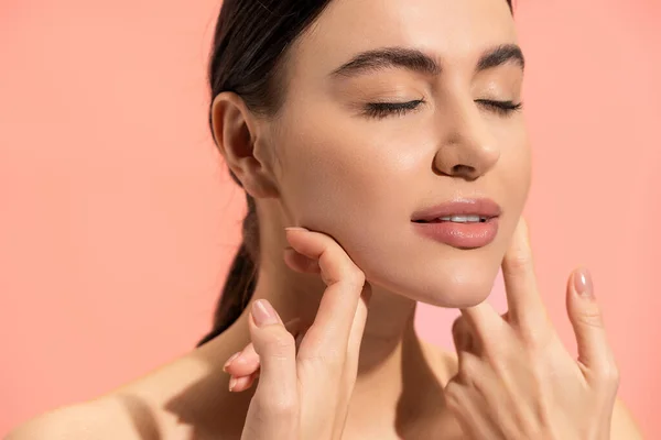 Brunette woman with soft skin doing face massage isolated on pink — Stock Photo