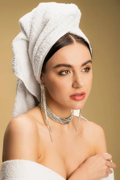 Young woman in luxurious jewelry posing with towel on head on beige — Stock Photo