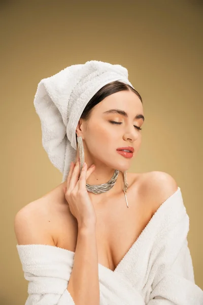 Elegant young woman with closed eyes and towel on head on beige background — Stock Photo